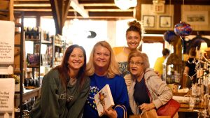 Group of smiling women shopping at a boutique in Benton County, Missouri, holding gifts and enjoying a small-town shopping day trip.