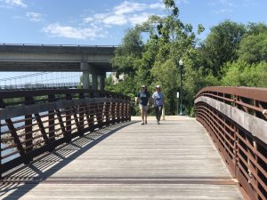 Two women walking across a pedestrian bridge near the waterfront in Warsaw, Missouri on a sunny spring day.